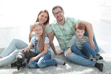 happy family sitting on the carpet in a new apartment