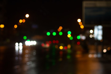 Fototapeta na wymiar Lanterns of the night city illuminate the road. Blurred photo with defocus. Headlights of cars in the night city. Multicolored bright festive night lights bokeh.