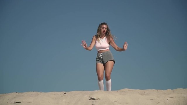 Attractive girl dancing twerk at the beach Tanned girl in short shorts moves her body standing on the sand Female is twerking outdoors Pretty lady dances passionately