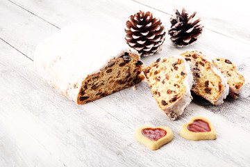Traditional European Christmas pastry, fragrant home baked stollen, with spices and dried fruit. Sliced on rustic table with xmas tree branches and decorations