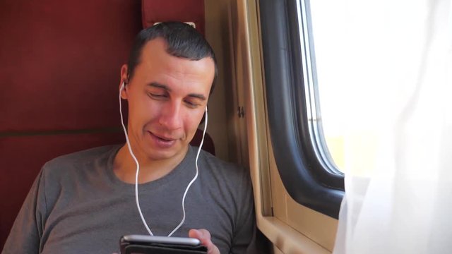 man listening to the music lifestyle on the train rail car coupe compartment travel. slow motion video. man with a smartphone at the window of a train in a car travel internet social media web. man