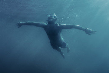 Fototapeta na wymiar Happy man swimming underwater.