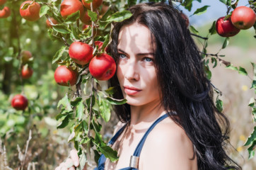 Fototapeta na wymiar Sexy brunette in a wild apple orchard. Portrait on the background apple branch. Female sexuality. Summer memories. Style Eve. Natural