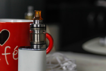 Electronic cigarette on club table in the living room.  Usually layout with electronic cigarettes and little things. Advanced model of electronic cigarette, e-cig