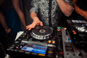 Obraz premium Dj mixes the track in the nightclub at party. In the background laser light show