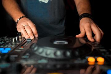 Dj mixes the track in the nightclub at party. In the background laser light show