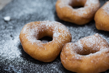 Homemade donuts with icing sugar powder on wooden background
