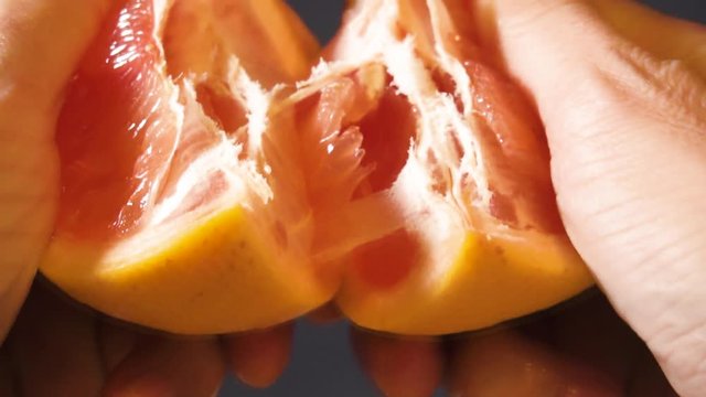 Man's hands tearing a fresh juicy grapefruit. Close-up.
