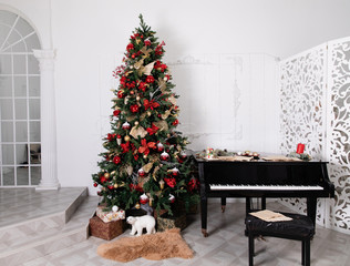 Christmas tree decorated with toys, lights and garland and piano
