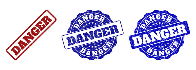 Fototapeta premium DANGER scratched stamp seals in red and blue colors. Vector DANGER signs with distress effect. Graphic elements are rounded rectangles, rosettes, circles and text labels.