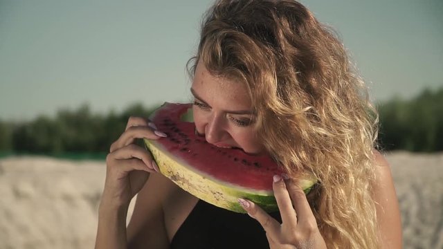 Portrait of sweet sexy woman with waving hair eating watermelon outdoors Cute irl enjoys her rest and smiles A slice of juicy watermelon in the hands of beatiful hot girl