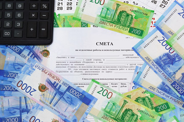 The form of the document with the Russian text Estimates for finishing works and the materials used. Russian money and calculator on the table