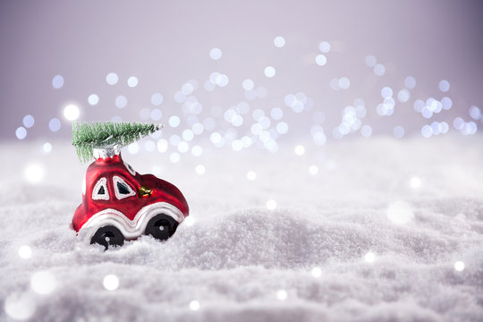 Cute little red car with christmas tree drives through winter landscape