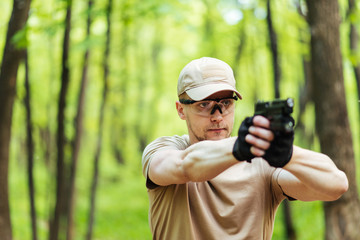 instructor with gun in forest leads aiming and posing on camera