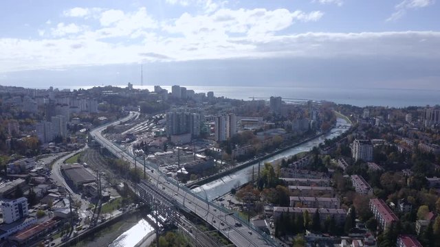 Aerial view car traffic on bridge over river in big city on sea landscape background. Car driving on urban highway, modern building in sea city. Drone view city infrastructure and sea on horizon