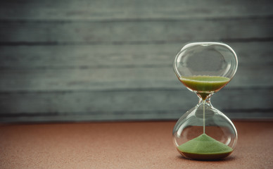 Sand running through the bulbs of an hourglass measuring the passing time in a countdown to a deadline, on a blur background with copy space