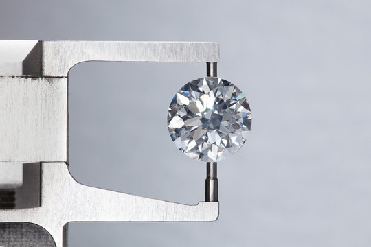 loose big brilliant round diamond is being measure by mm gauge and weight estimator for size