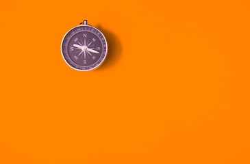 Black compass on orange background, equipment for travel, tourism and business, top view and copy...