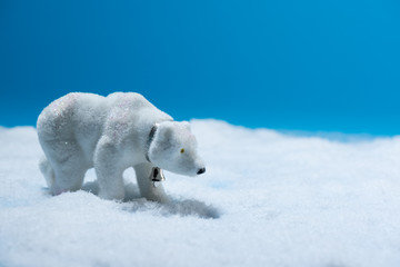 Decorative toy polar bear in faux snow with blue background.