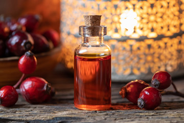 A bottle of rose hip seed oil with dried rose hips