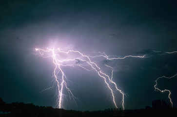 Several multiple branched and forked lightning bolts strike down to earth from a severe...