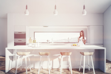 White kitchen with bar and ovens, woman