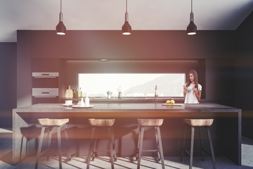 Dark gray kitchen with bar, woman