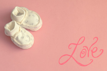 white baby's bootees on pink background