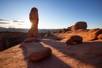 Beautiful landscape of the unique sandstone rock formation in the desert during a sunny sunset. Taken in Arches National Park, Moab, Utah, United States.