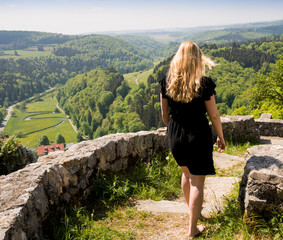 Naklejka premium young woman walks with waving long hair on a ruin above the Lautertal valley