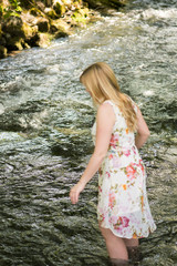 young blond girl looking down with long blond hair in nature