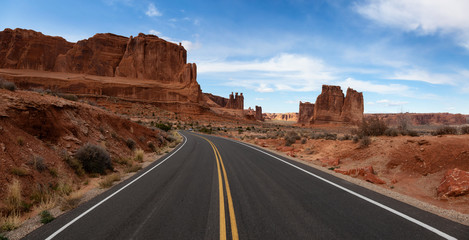 Panoramic landscape view of a Scenic road in the red rock canyons during a vibrant sunny day. Taken in Arches National Park, located near Moab, Utah, United States.