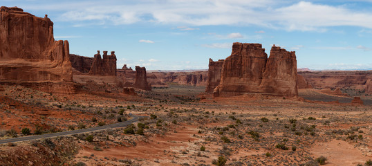 Panoramic landscape view of a Scenic road in the red rock canyons during a vibrant sunny day. Taken in Arches National Park, located near Moab, Utah, United States.