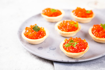 Holidays composition. Red Salmon Caviar in tartlet on a plate. Festive Appetizer  on  gray background.Copy space for Text. 
