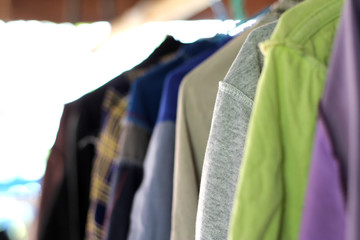 Gray cloth hanging on hanger with many clothes.