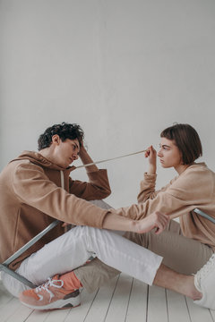 Woman pulling cord on hoodie of man
