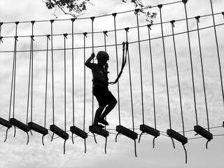 Junge mit Helm und Ausrüstung auf einer wackeligen Hängebrücke im Kletterpark in Sapanca bei...