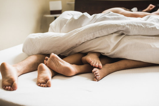 Three pairs of legs sticking out from under the blanket