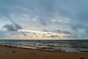 storm clouds forming over clear sea beach with rocks and clear sand