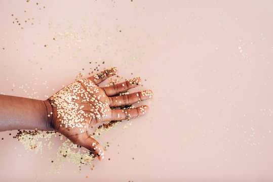Black girl's palm with golden confetti