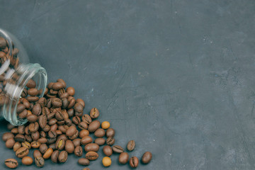 roasted coffee beans poured from a glass jar. angular placement of the coffee object. on dark...