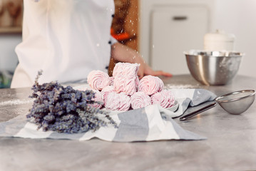 Close up hands of the chef sprinkles homemade marshmallows with sugar powder. Marshmallow preparation process. The concept of home cuisine.