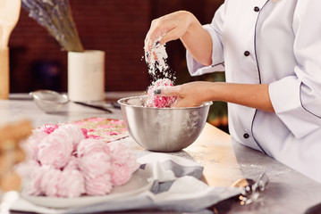 The chef sprinkles homemade marshmallows with sugar powder. The concept of home cuisine. Marshmallow preparation process.