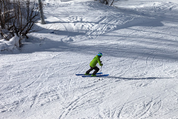 Skier descent on snowy ski slope at sunny winter day