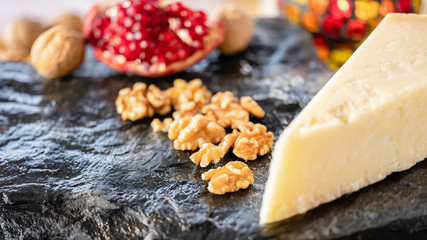 Parmazan cheese with pomegranate and seeds with nuts on the natural black stone