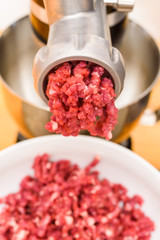 Raw meat coming out of the meat grinder as it is being minced.