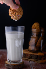 Appetizing and tasty oatmeal cookies with raisins and milk in a dark vein on the table