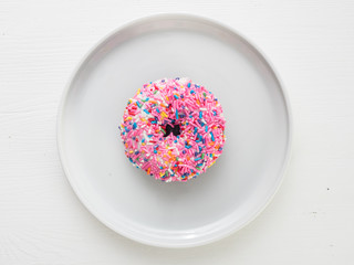 Classic donut with pink frosting and colorful sprinkles
