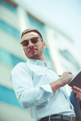 Handsome young man writes in notebook outdoors