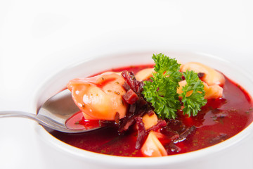 Traditional polish Christmas Eve dish: red borscht with uszka a mushroom filled kind of dumpling decorated with parsley eaten with a spoon